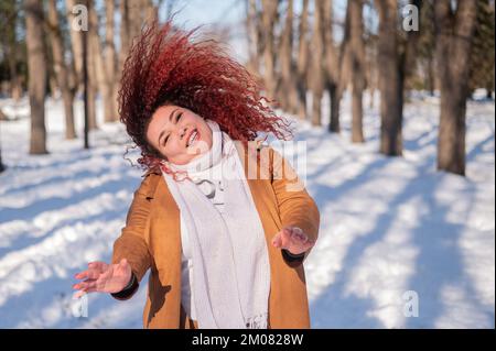 Die fette kaukasische Frau tanzt im Winter auf einem Spaziergang im Park. Stockfoto