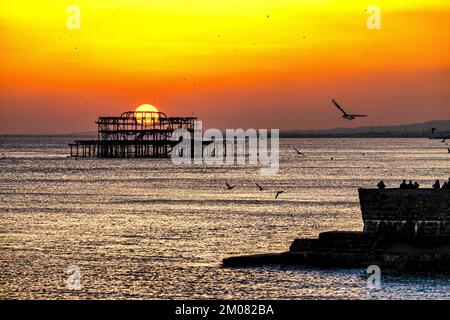 Der Blick auf den Brighton West Pier im Meer vor dem orangefarbenen Sonnenuntergang Stockfoto