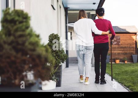 Blick von der Krankenschwester im Hinterzimmer, die sich um eine ältere Dame kümmerte, die Seite an Seite in den Garten ging Stockfoto