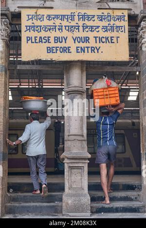 Gepäckträger mit Fischkörben auf dem Kopf, die in den Chhatrapati Shivaji Maharaj Terminus (CMST) in Mumbai, Indien, einfahren, um die Körbe mit dem Zug weiterzuleiten Stockfoto