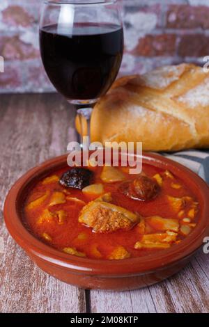 Tonauflauf mit eingekochtem, typisch spanischem Essen im Madrider Stil auf einem Holztisch mit einer Backsteinwand im Hintergrund. Stockfoto