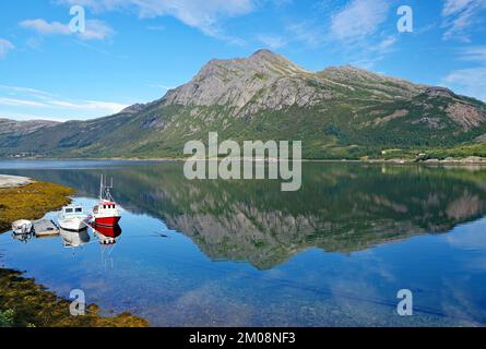 Kleine Fischerboote und steile Berge im Wasser eines Naturhafens, Jektvik, FV 17, Kystriksveien, Nordland, Norwegen, Europa Stockfoto