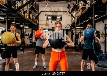 Sportliche Sportler in Sportbekleidung, die beim Training im industriellen Fitnessstudio trainieren. Gruppentraining, Teamwork-Konzept. Horizontale Aufnahme. Vorderansicht Stockfoto