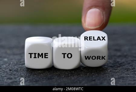 Die Hand würfelt und ändert den Ausdruck „Arbeitszeit“ in „Zeit zum Entspannen“. Stockfoto