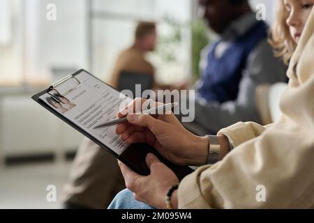 Nahaufnahme einer jungen Frau beim Ausfüllen des Antragsformulars im Einwanderungsamt, Kopierraum Stockfoto