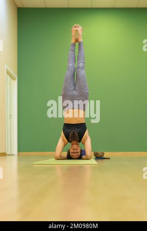 Vertikales Foto eines Yoga-Lehrers in Shirshasana-A-Haltung Stockfoto