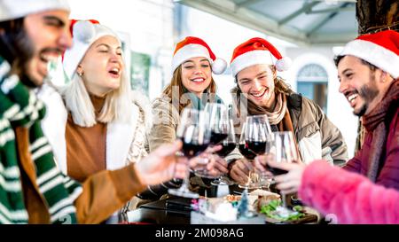 Trendige junge Leute auf dem weihnachtsmann feiern Weihnachten mit Rotwein auf dem Food Street Market - Winterfreundschaftskonzept Stockfoto