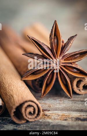 Sternanisstöcke und Zimtstangen aus der Nähe auf einem Holzhintergrund. Stockfoto