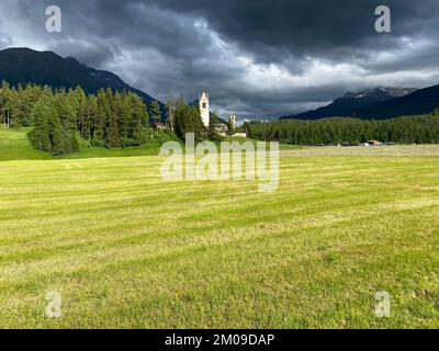 Stürmischer Himmel über einer grünen Lichtung in der Nähe der Kirche San Gian in Celerina, Schweiz Stockfoto