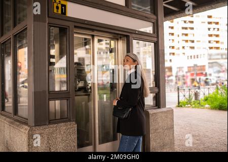 Langhaarige Frau in schwarzem Mantel, die in die U-Bahn kommt Stockfoto
