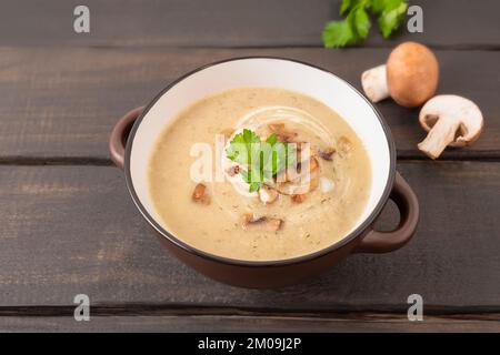 Schüssel mit Pilzcreme-Suppe auf einem Holztisch Stockfoto