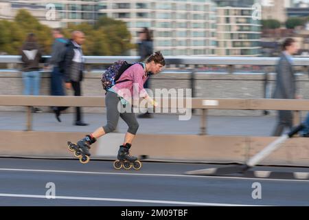 Eine Frau, die während der Hauptverkehrszeit mit Rollerblades über London Bridge, London, Großbritannien pendelt. 18. Okt. 2022 Stockfoto