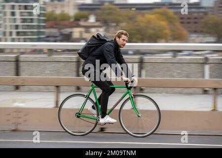 Ein Mann pendelt mit dem Fahrrad während der Hauptverkehrszeit über die London Bridge, London, Großbritannien. 18. November 2022 Stockfoto