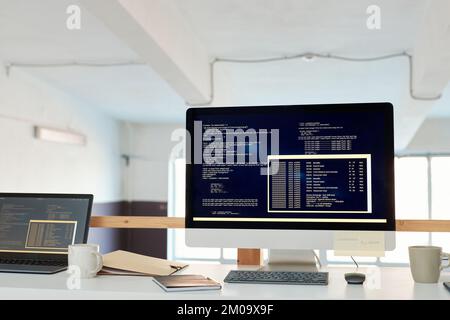 Computer mit Programmiercode auf dem Bildschirm auf dem Schreibtisch des Software-Entwicklers Stockfoto