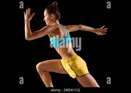 Junge Sportlerin, Läufer und Jogger in Bewegung isoliert auf schwarzem Hintergrund. Sport, Fitness, Energie, Bewegungskonzept Stockfoto