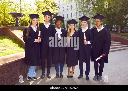 Bereit zum Erfolg. Sechs College-Absolventen stehen hintereinander und lächeln. Stockfoto