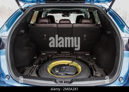 Reserverad im Kofferraum eines modernen Autos. Wagenheber anheben und Ersatzreifen hinten im Fahrzeug. Stockfoto