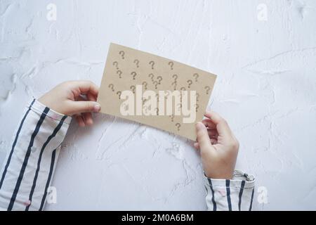 Kind mit Fragezeichen auf weißem Hintergrund Stockfoto