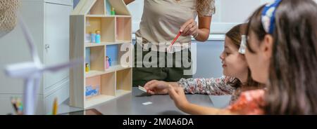 Die Lehrerin erklärt ihren Schülern die Teile eines nachhaltigen Hauses Stockfoto