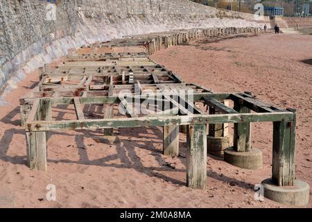 Holzstützen entlang der Ufermauer am Strand von Corbyn, Torquay, die während der Sommersaison als Basis für Strandhütten verwendet werden (im März gesehen) Stockfoto