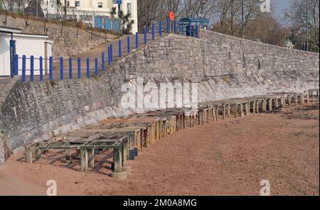 Holzstützen entlang der Ufermauer am Strand von Corbyn, Torquay, die während der Sommersaison als Basis für Strandhütten verwendet werden (im März gesehen) Stockfoto