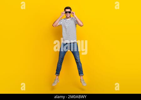 Foto des coolen, beeindruckenden Mannes mit weißem T-Shirt, dunkle Brille, die bis in den dunklen Hintergrund springt Stockfoto