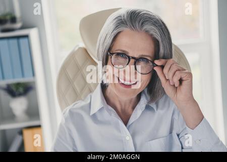 Porträt einer positiv fröhlichen, cleveren Person Sessel Armband berühren Brille Zahnfleisch lächeln Online Webinar modernes Büro im Inneren Stockfoto