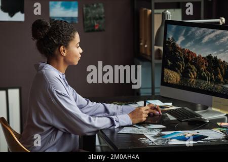 Junge Fotografin, die Fotos der Natur am Computer bearbeitet Stockfoto