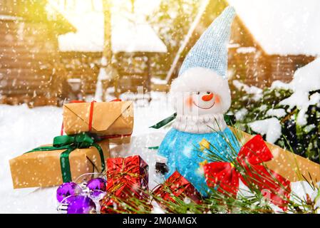 Ein Schneemann mit Geschenken und Spielzeug steht im Schnee. Hintergrund für Neujahr oder Weihnachten Stockfoto