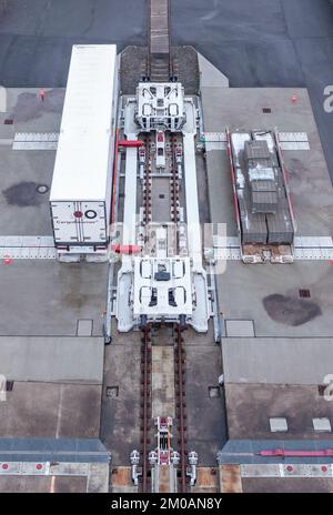 05. Dezember 2022, Sachsen, Leipzig: Ein Auflieger wird an einem Güterbahnhof mit einer neuen Ladetechnik auf einen Eisenbahnwagen verladen. Das Leipziger Unternehmen CargoBeamer möchte den Güterverkehr innerhalb Europas effizienter und umweltfreundlicher gestalten. Im neu entwickelten Terminal können Lkw-Anhänger mit Hilfe einer sogenannten Laderampe seitlich auf den Waggon gefahren werden. Dadurch wird das Problem umgangen, dass fast alle Lkw-Anhänger nicht mit einem Kran angehoben werden können, was die Beladung der Schiene kostspielig und nicht lohnenswert macht. Das erste Terminal des Unternehmens ist in Calais in Nordfrankreich in Betrieb Stockfoto