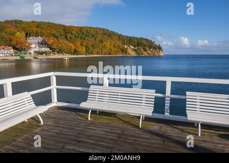 Terrasse mit Bänken auf dem hölzernen Orlowo Pier an der Ostsee in Gdynia, Polen, mit Blick auf die Orlowski-Klippe im Herbst. Stockfoto