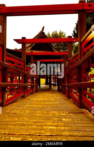 Ein Holzsteg durch einen Bogen im chinesischen Stil im Garten Stockfoto