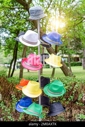 Kleiderbügel mit Hüten auf der Straße. Stockfoto