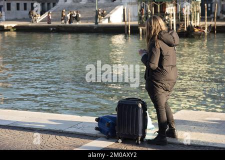 Blick von hinten auf eine junge Frau mit Gepäck in Venedig, Italien Stockfoto