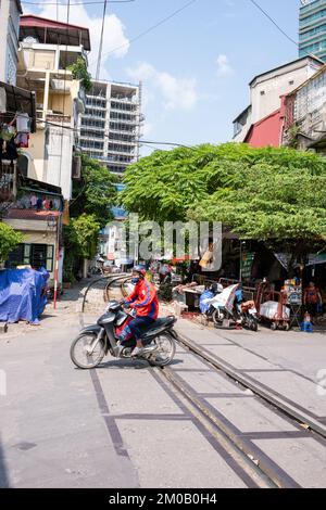 Hanoi, Vietnam - 16. September 2018: Junger Mann im Trainingsanzug überquert die Bahnstrecke auf seinem Roller Stockfoto