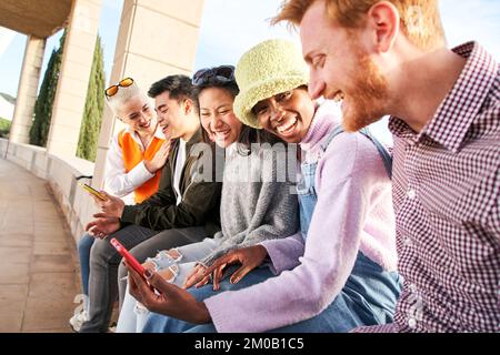 Gruppe junger Menschen gemischter Rassen mit Mobiltelefonen. Aufgeregte Schüler, die Zellen benutzen. Konzept von jungen Unternehmergeist, freundlich, Selfie, App, Hipster Stockfoto