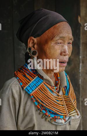 Mon, Nagaland, Indien - 03 03 2009 : Portrait der alten Naga Konyak-Stammesfrau in traditioneller Halskette und Ohrringen mit schwarzem Kopftuch Stockfoto