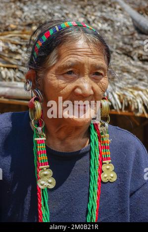 Mon, Nagaland, Indien - 03 03 2009 : Porträt der alten Naga Konyak-Stammesfrau vor ihrem Dorfhaus mit Ohrringen und traditionellem Schmuck Stockfoto