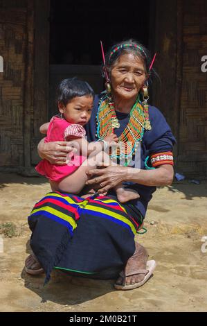 Mon, Nagaland, Indien - 03 03 2009 : Porträt der alten Naga Konyak-Stammesfrau, die mit dem Enkel sitzt und traditionellen bunten Schmuck trägt Stockfoto