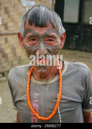 Mon District, Nagaland, Indien - 03 09 2014 : Portrait des alten Naga Konyak Stamm-Kopfjäger-Kriegers mit traditionellem Gesichtstattoo und Korallenkette Stockfoto