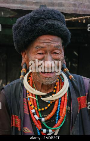 Mon District, Nagaland, Indien - 03 09 2014 : Old Naga Konyak Stamm Kopfjäger Krieger mit Gesichtstätowierung, Hornohrringen und Halskette mit Eberstoßern Stockfoto