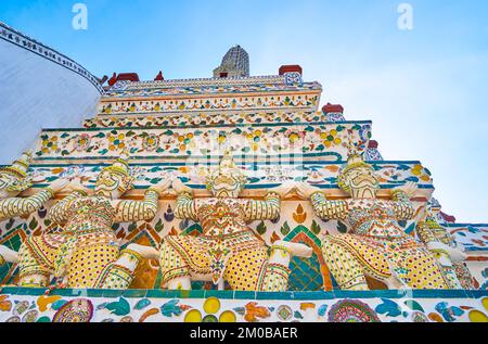 Farbenfrohe Porzellanskulpturen von Yakshas - den Geisterwächtern, an der Wand des Wat Arun Tempels in Bangkok, Thailand Stockfoto