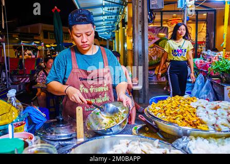 BANGKOK, THAILAND - 23. APRIL 2019: Der junge Koch auf der Khaosan Road bereitet thailändische Gerichte mit gedämpften Meeresfrüchten auf dem Nachtmarkt am 23. April in Bangkok zu Stockfoto