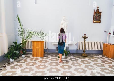 Das Mädchen betet in der Kirche. Kirchengemeinde. Christlicher Glaube. Lesen vor dem Symbol. Gebetszeit. Stockfoto