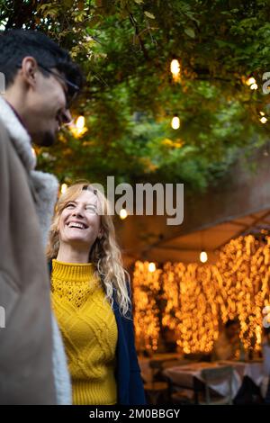 Selektiver Fokus auf glückliche blonde Frau, die mit einem Freund spricht Stockfoto