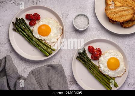 Lebensmittelfotografie von Spiegeleiern, Tomaten, Spargel, Toast, Salz, Frühstück Stockfoto