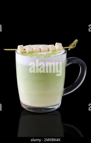 Matcha Latte mit Kokosnussstücken auf Spieß auf schwarzem Hintergrund Stockfoto