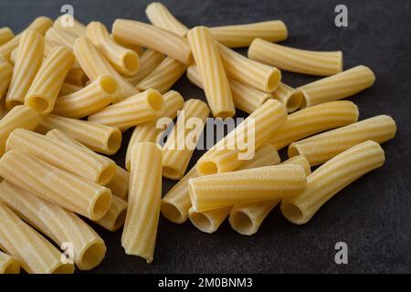 Rohe italienische Penne rigate Pasta isoliert auf schwarzem Hintergrund Stockfoto