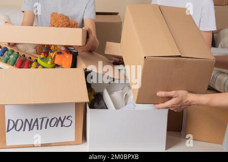 Freiwillige sammeln Spenden für wohltätige Zwecke, um Familien mit niedrigem Einkommen zu helfen. Spendenboxen mit Kleidung, Bettwäsche, Haushalts- und Hygieneartikeln, Lebensmitteln, Spielzeug Stockfoto