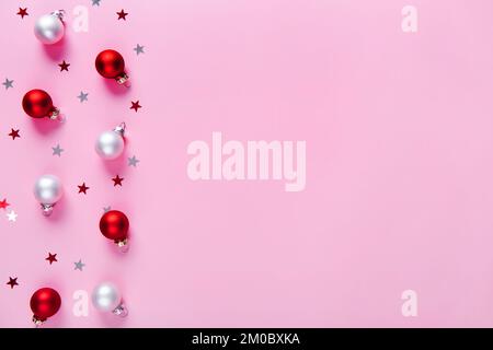 Kreatives Urlaubsmuster. Weihnachtlicher Hintergrund mit roten und weißen Kugeln auf pinkfarbenem Hintergrund. Stockfoto